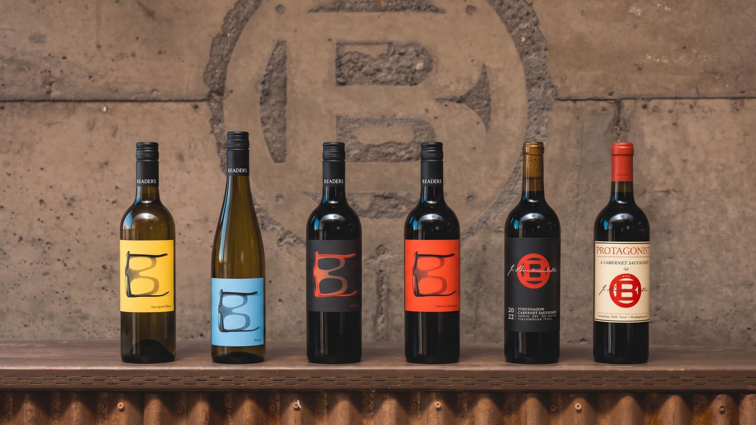 The J. Bookwalter lineup of Readers, Foreshadow and Protagonist wines in front of a concrete wall cast with the winery's B emblem