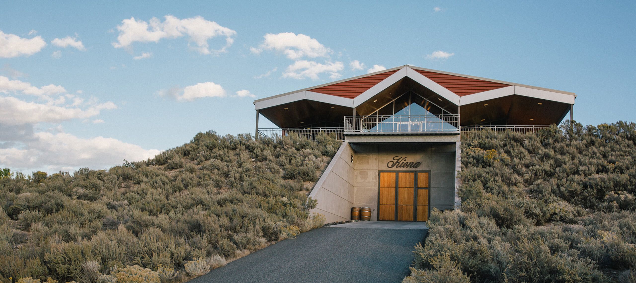 The Kiona tasting room perched atop a sagebrush hillside, with the script Kiona sign above the cellar doors built into the slope