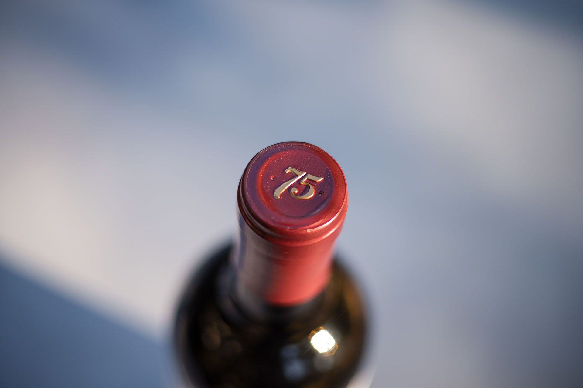 Top-down view of the 75 Wine Co bottle cap with gold 75 emblem against open sky