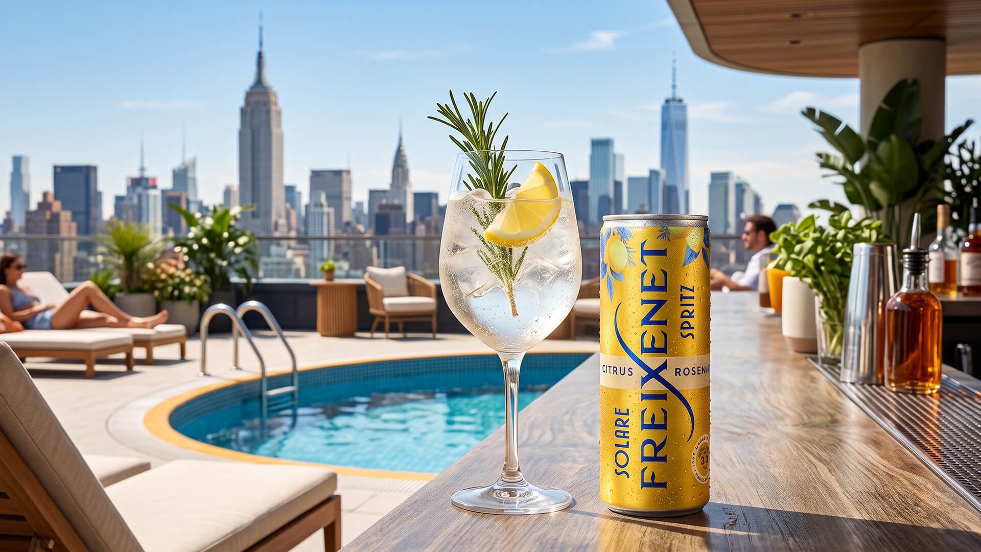 Chilled Freixenet Solare Spritz can and a garnished spritz glass on a rooftop pool bar, Manhattan skyline behind