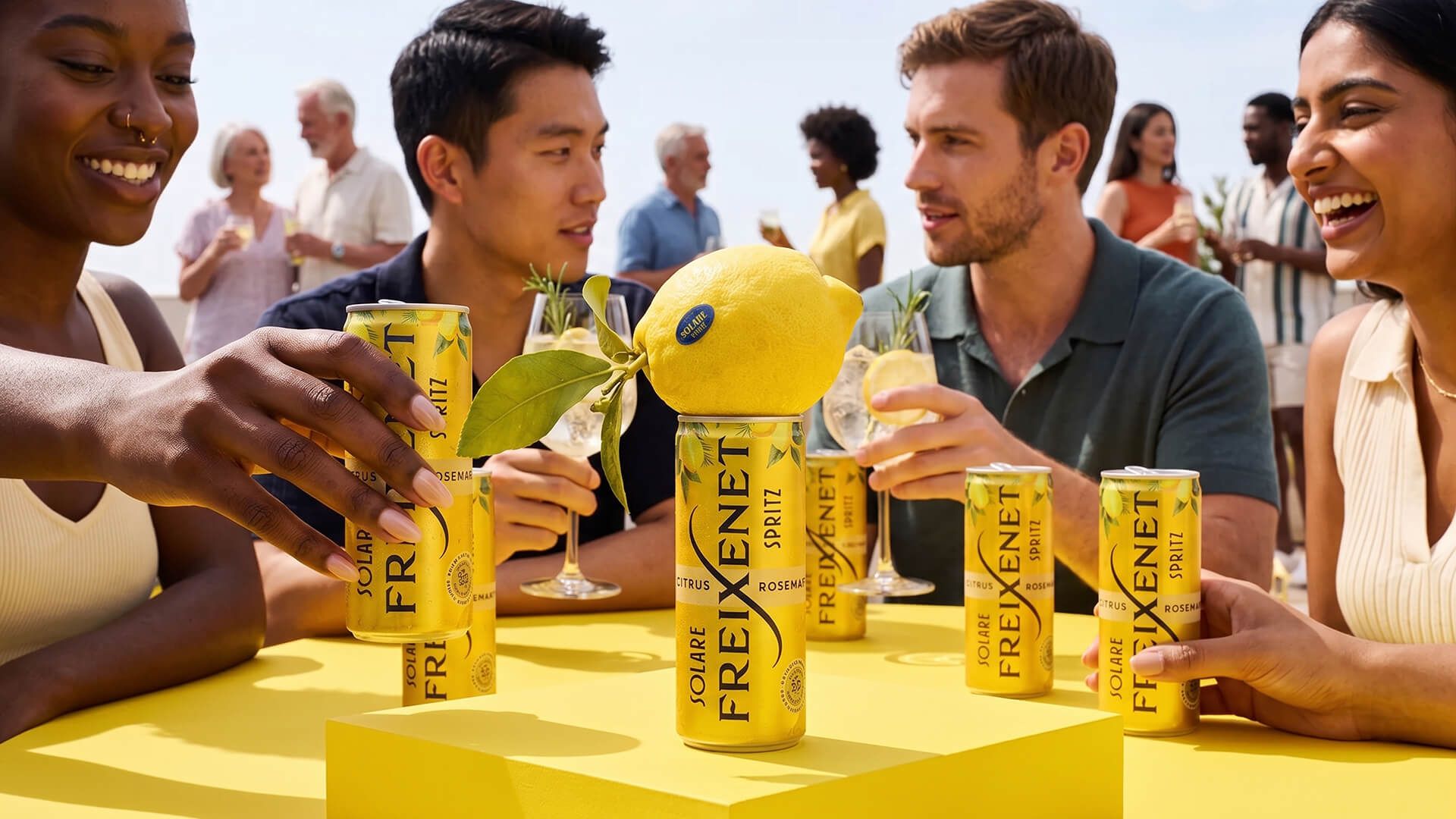 Friends laughing around a bright yellow table at a rooftop party, Freixenet Solare Spritz cans in hand and a lemon-topped can at the center